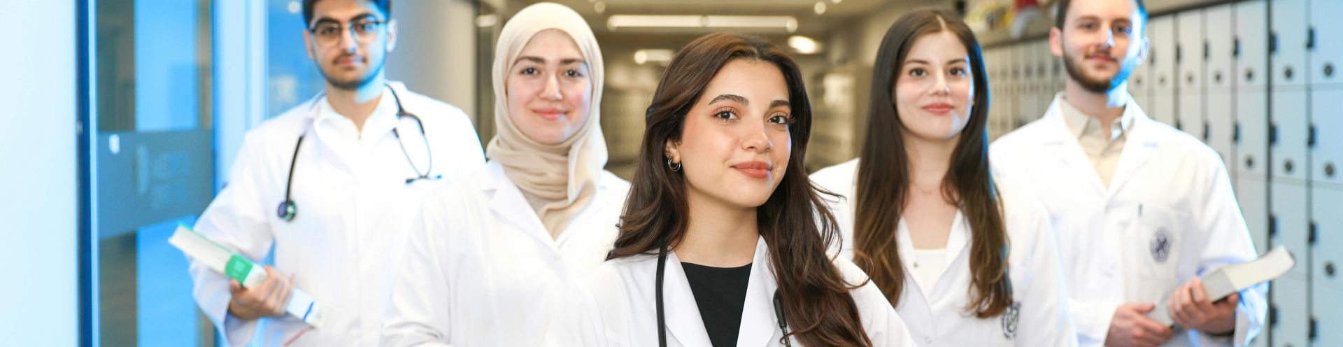 Group of diverse medical students wearing lab coats in university corridor, representing future healthcare professionals.